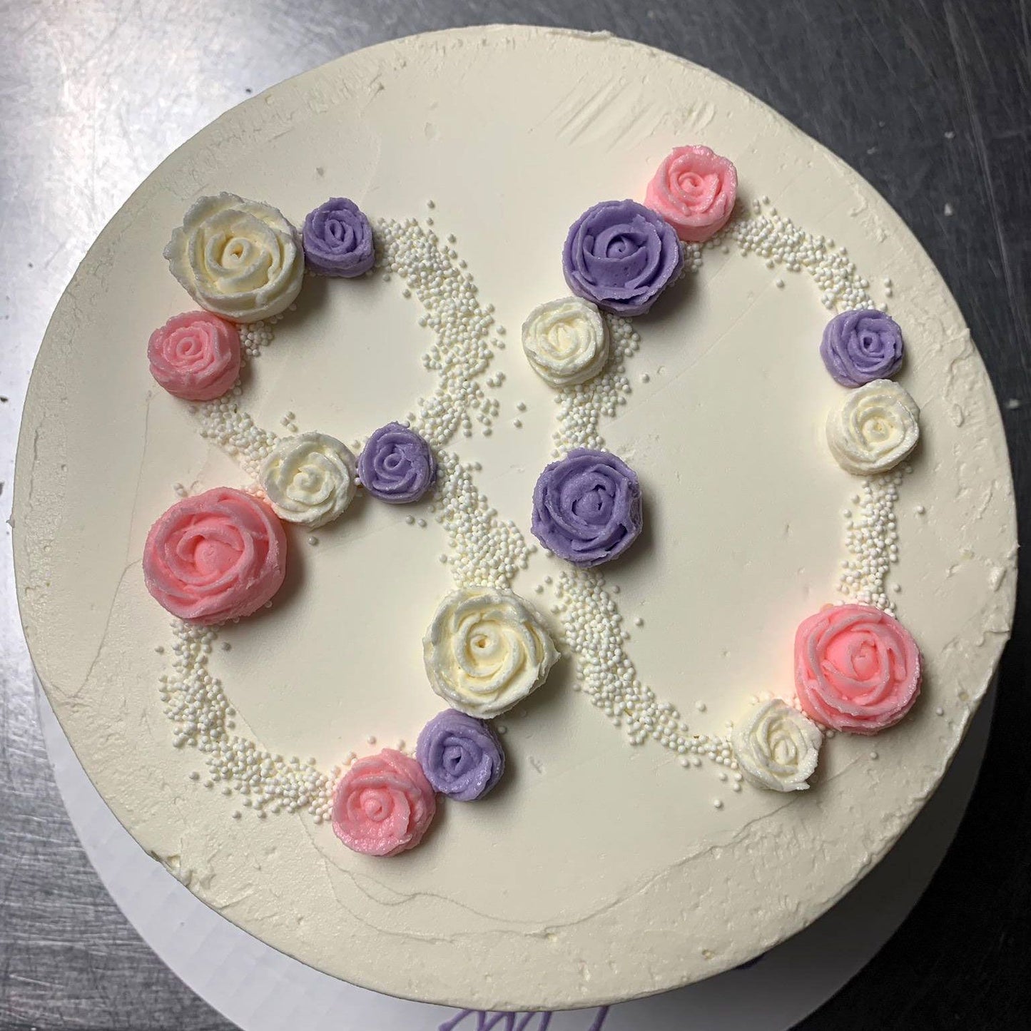 Decorative cake with pastel-colored flowers in the shape of the number "80" on white frosting. 