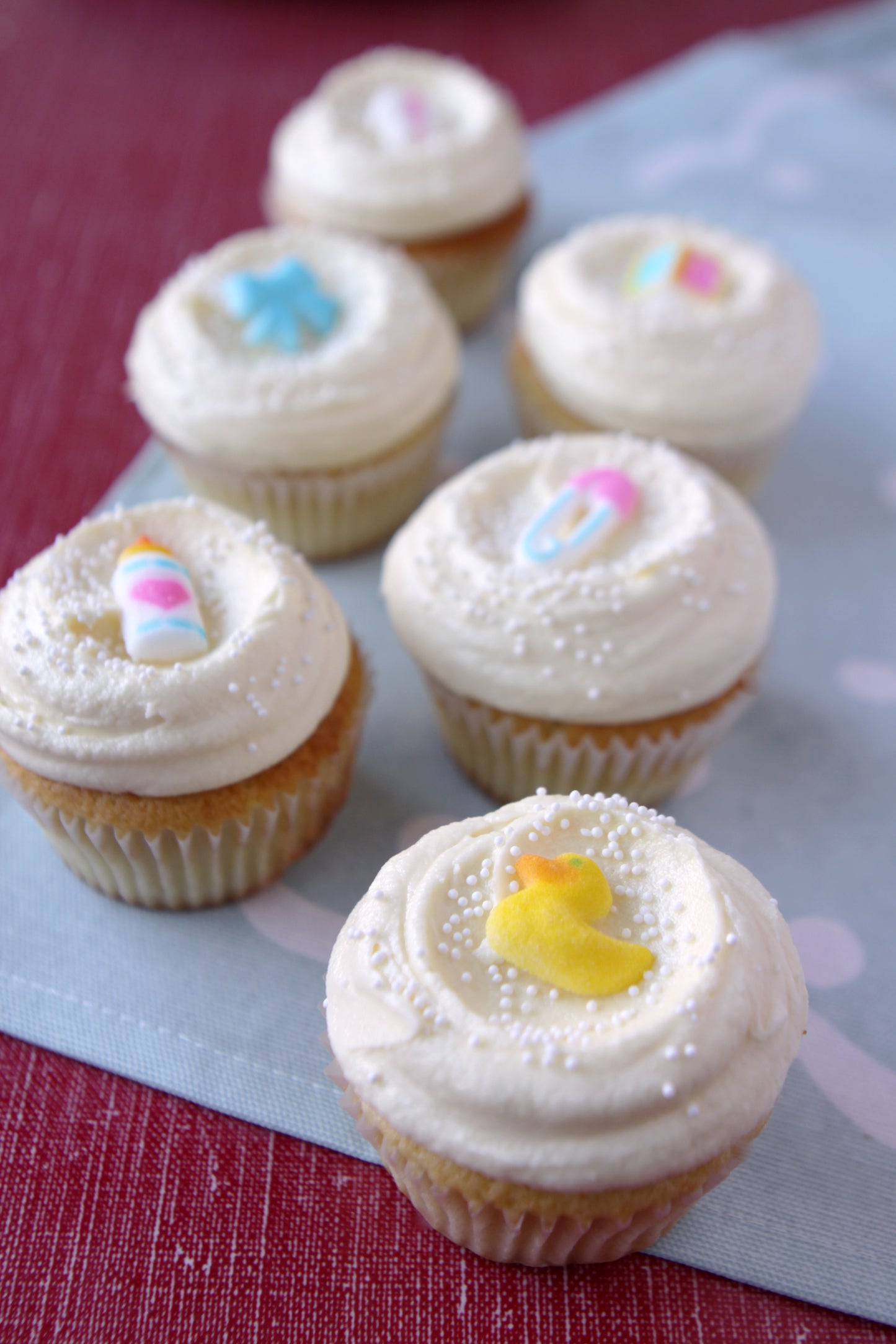 Cupcakes with white frosting and colorful decorations on a red surface