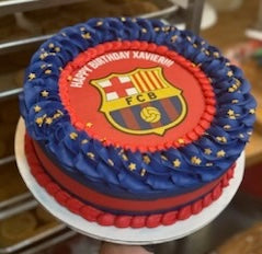 Birthday cake with FC Barcelona theme on a table.