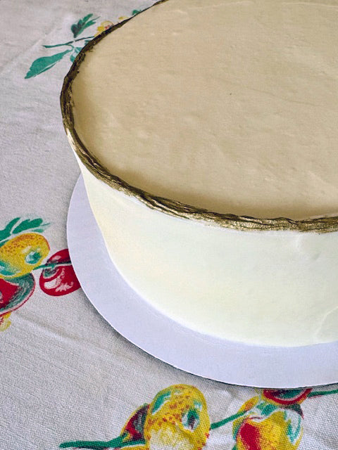 White cake with gold trim on a floral tablecloth