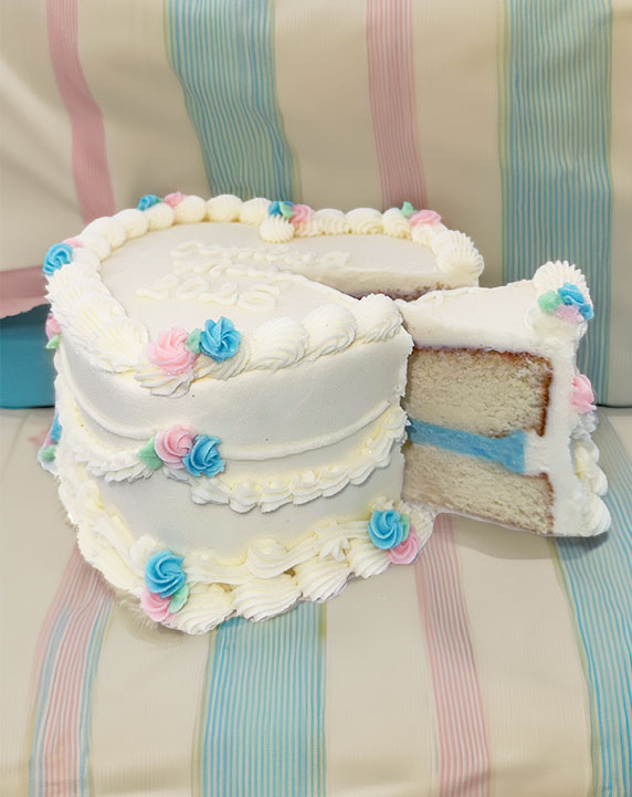 Heart-shaped cake frosted in white buttercream with tiny pastel blue and pastel pink rosettes. Filled with a pastel blue frosting between the cake layers. 