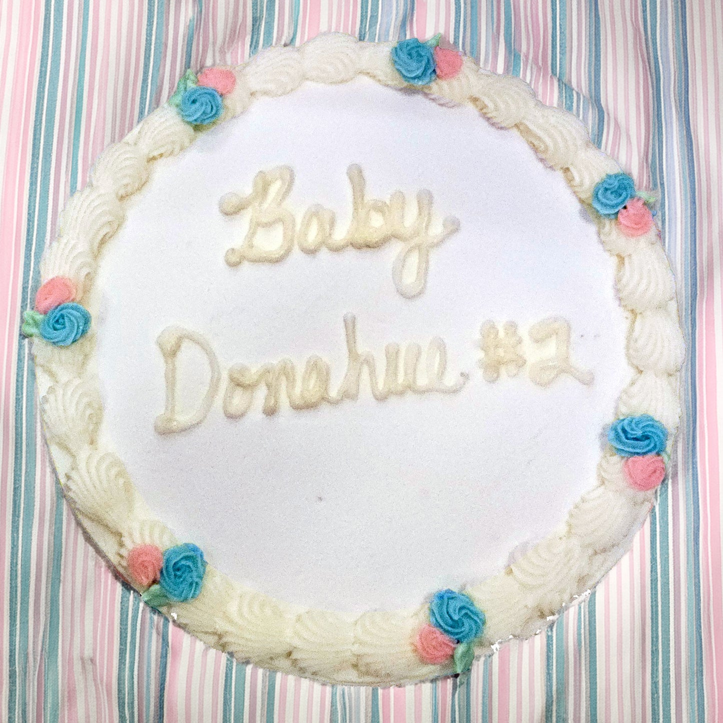Round cake with 'Baby Donahue #2' written on it against a striped background
