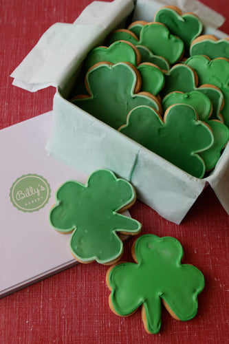 A child holding a green shamrock-shaped sugar cookie.