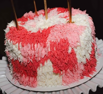 Chevron-patterned cake with pink and white frosting on a platter.